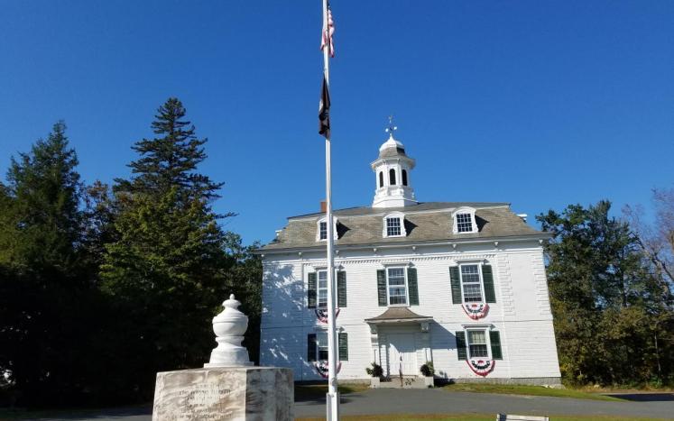 two story white building with flag pole in front